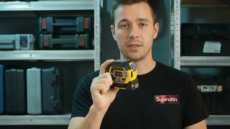Man holding a yellow device in a workshop setting with shelves in the background